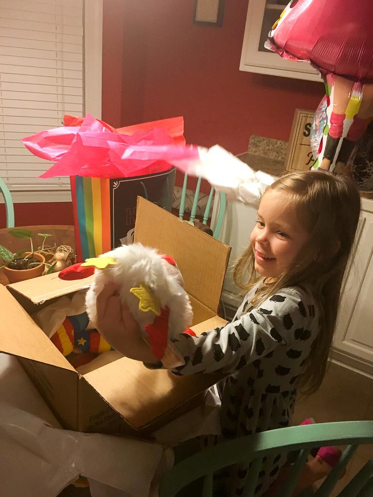 little girl opens birthday presents at home 