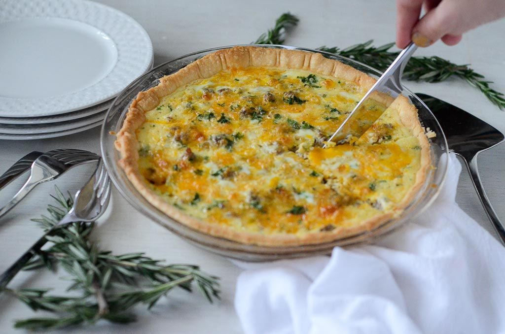 person cuts sausage and cheeese quiche with knife 