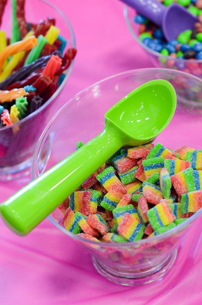 glass bowls of colorful candy with green ice cream scoop on table