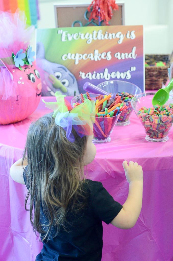 little girl checks out Trolls party table at her Cupcakes and Rainbows party
