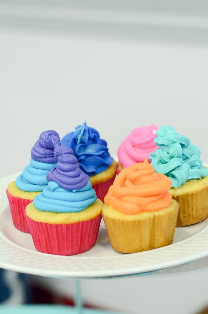 colorful Trolls cupcakes on white plate at Trolls birthday party