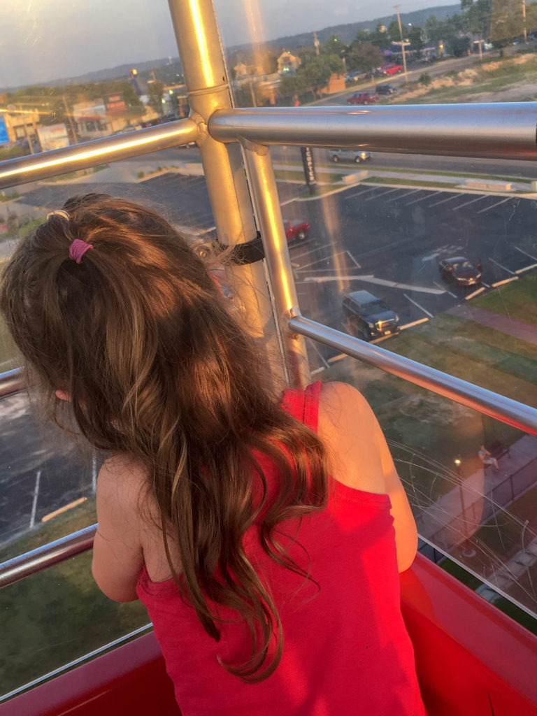 little girl looks out of window while riding the ferris wheel on Branson Strip 