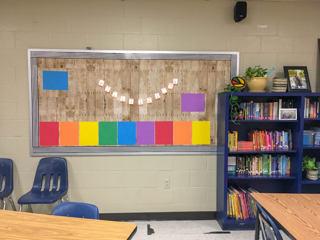 boho rainbow classroom theme with a rainbow bulletin board beside big blue bookcase 