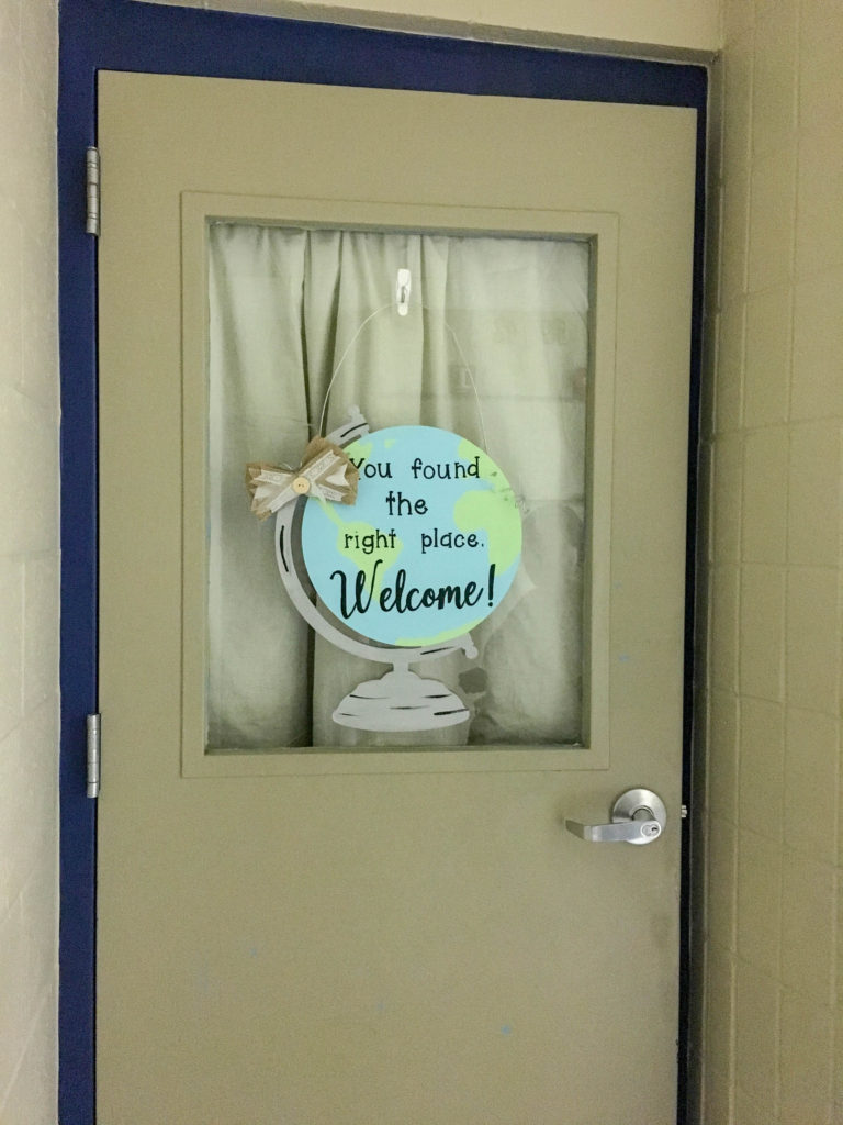 classroom welcome door hanger with globe hangs on beige classroom door