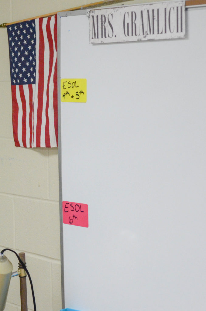 distressed metal nameplate for teacher hangs on board beside American flag