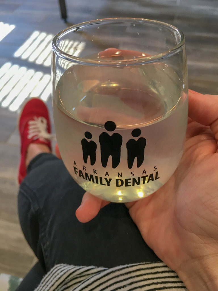 woman holds Arkansas Family Dental glass in hand 