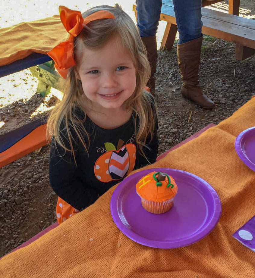 little girl smiles at a pumpkin patch birthday party 