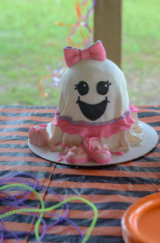 a Halloween birthday cake with a cute ghost face on a party table at cute ghost party for kids 