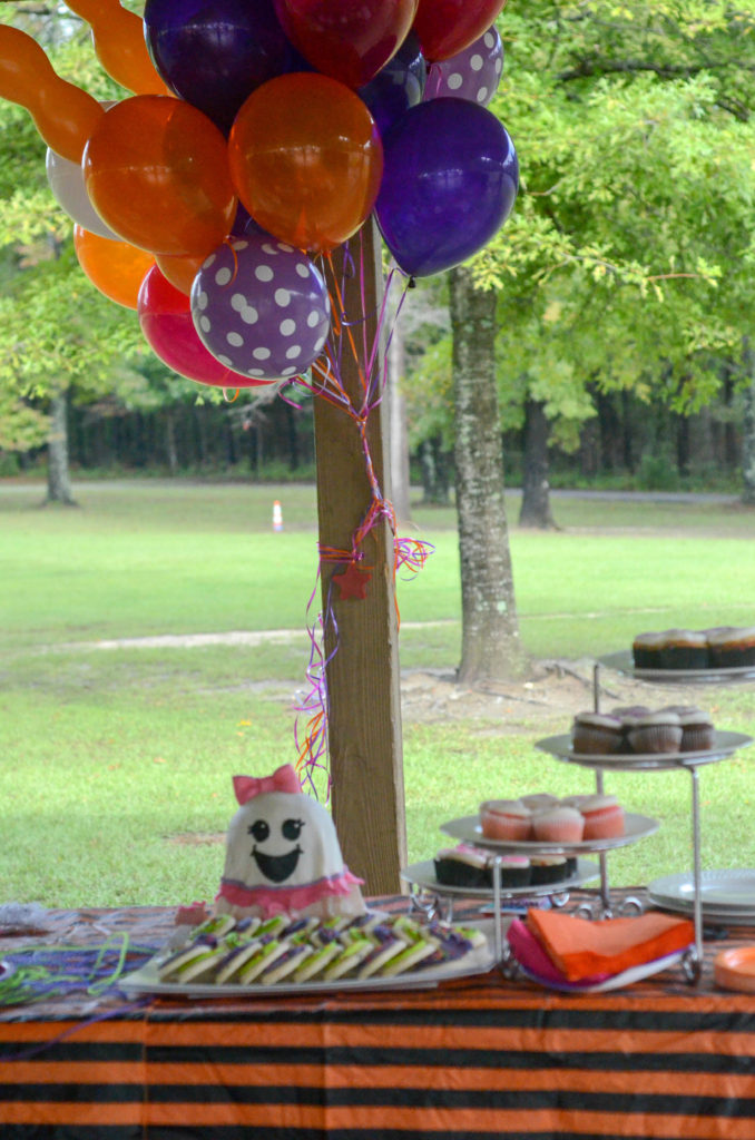 ghost party table with a ballerina birthday cake with a cute ghost face and colorful balloons