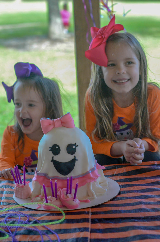 two girls laugh at a party table at a little girls halloween party with a ballerina ghost cake 