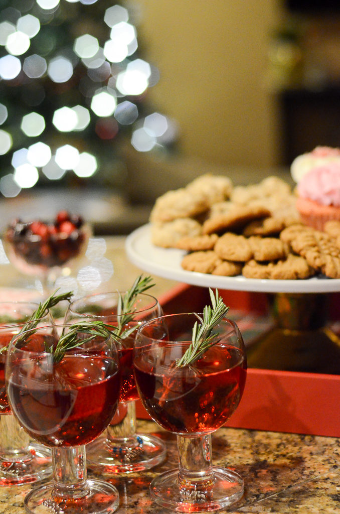 3 glasses of cranberry mocktail or cranberry cocktail with cookies and Christmas tree in back 