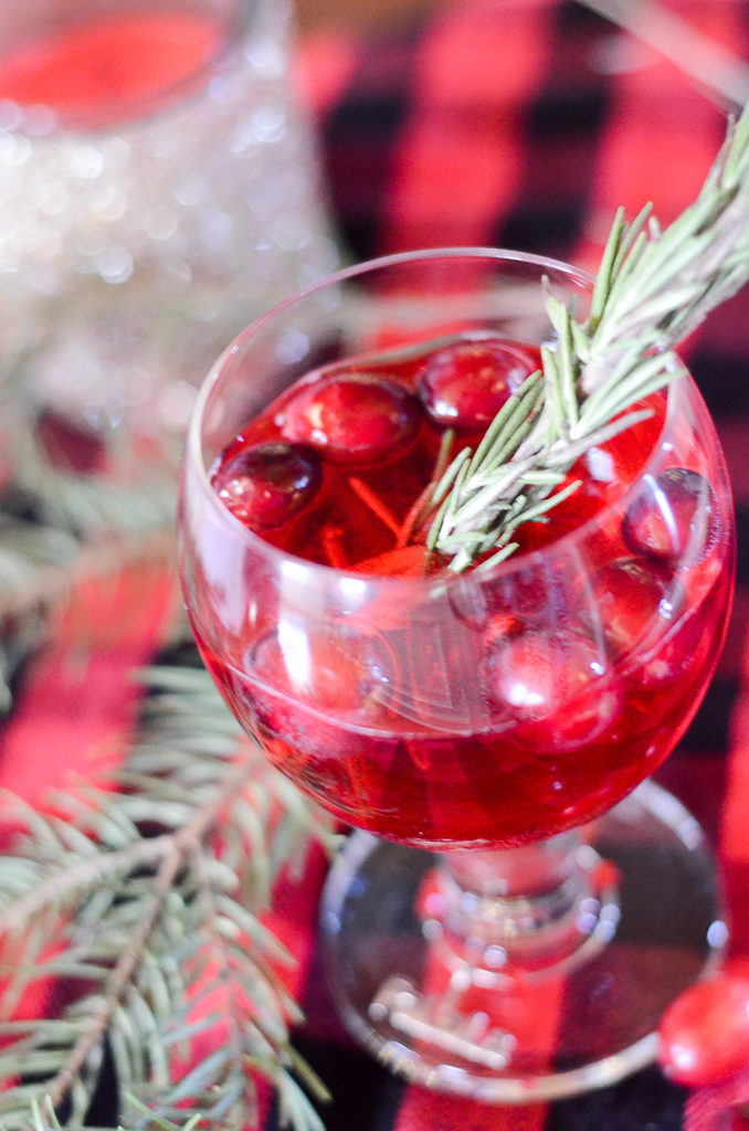cranberry juice mocktail in glass with rosemary and buffalo print tablecloth 
