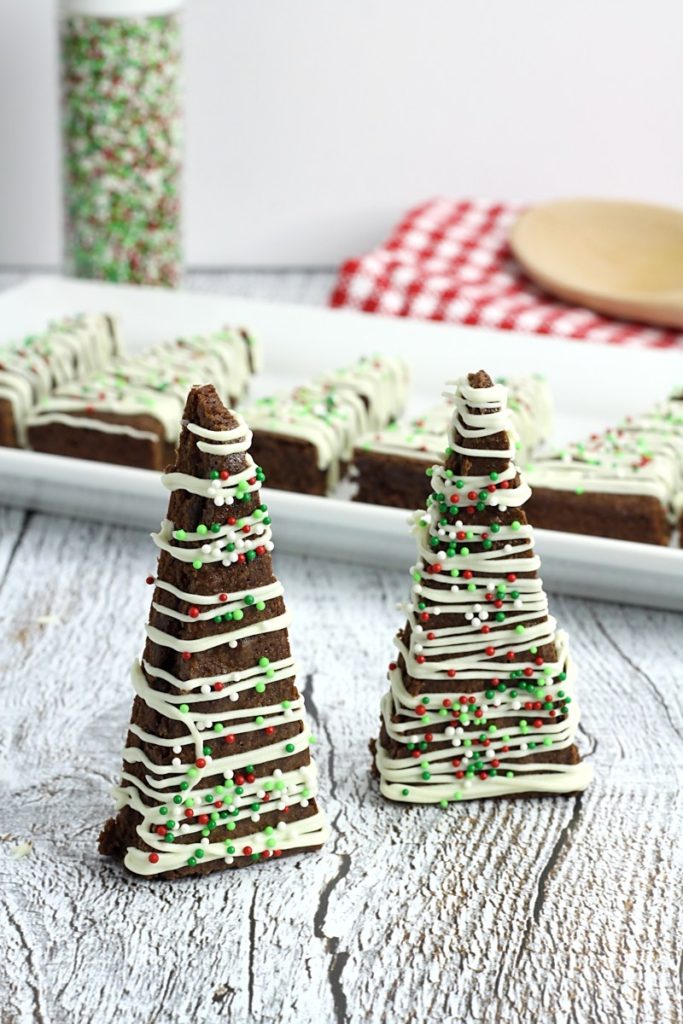 Christmas brownies shaped like Christmas trees and standing on white wood backdrop 