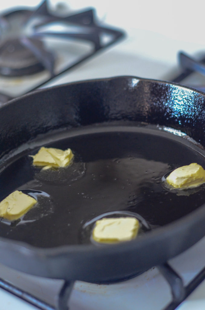 pats of butter sizzling in black cast iron skillet