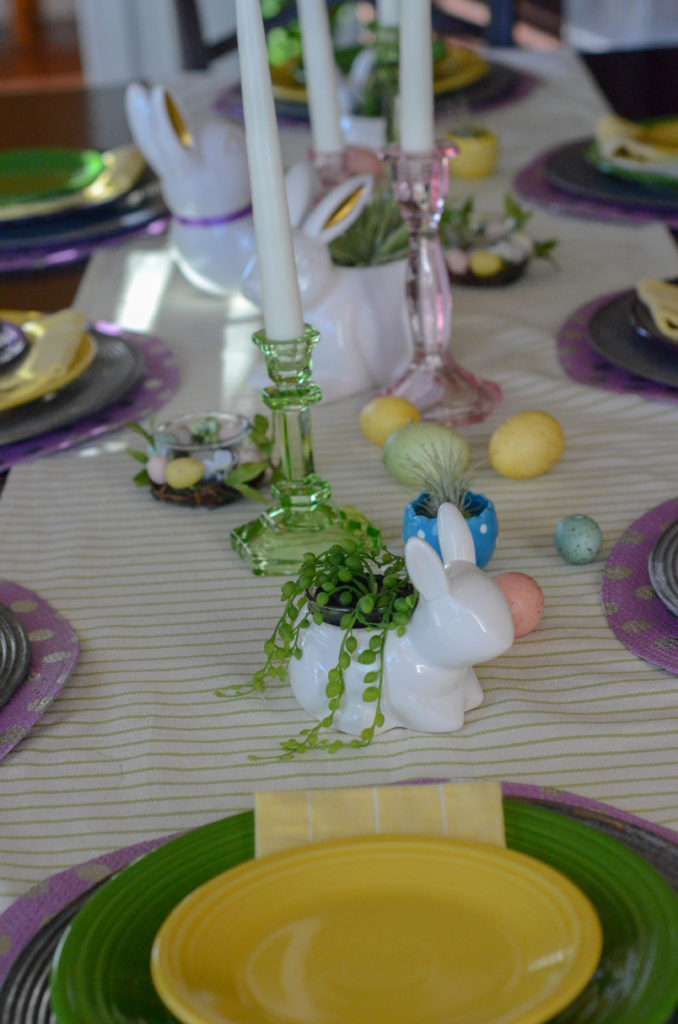 This spring table setting is the perfect modern and simple tablescape for Easter dinner - whether for kids, adults or a mix of both! The fun color combinations, the centerpieces, the placemats, the candles, the decorations, the runner, and the tableware bring a modern and playful vibe to Easter brunch or Easter dinner. The succulents bring a natural decor element to the table and play against the table settings of yellow, bright green, and purple. 