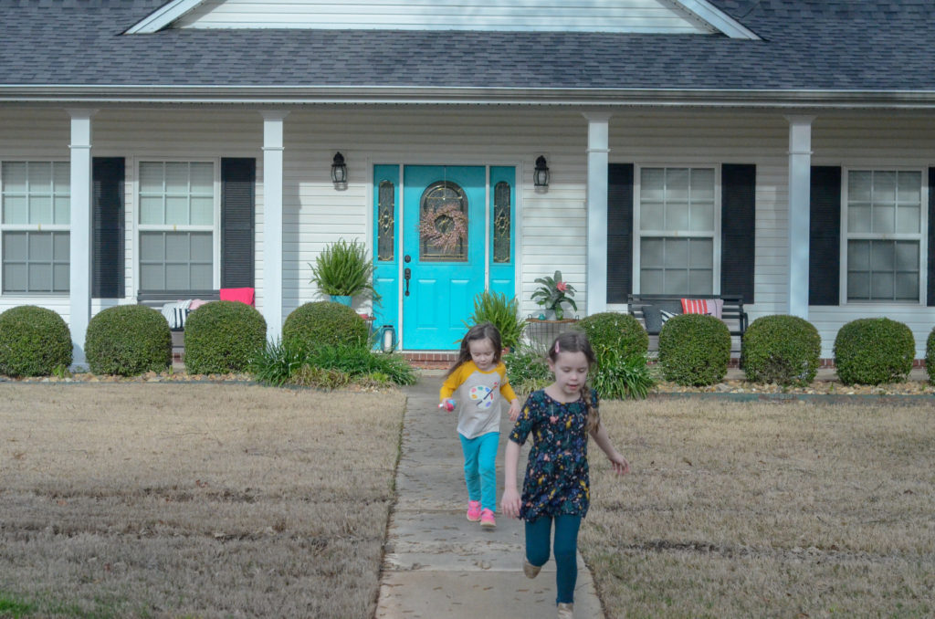 children run in front of a painted front porch with spring front porch ideas in pink and teal