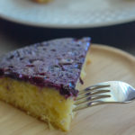 piece of blueberry upside down cake on wooden plate with fork