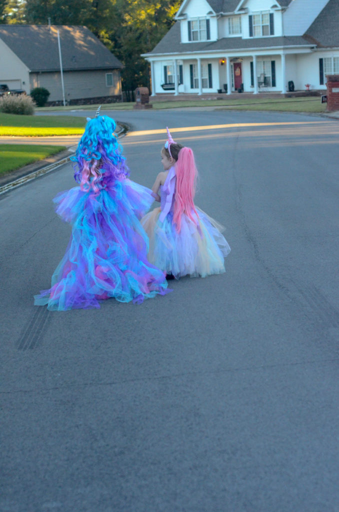 two sisters dressed for Halloween walk down the street 