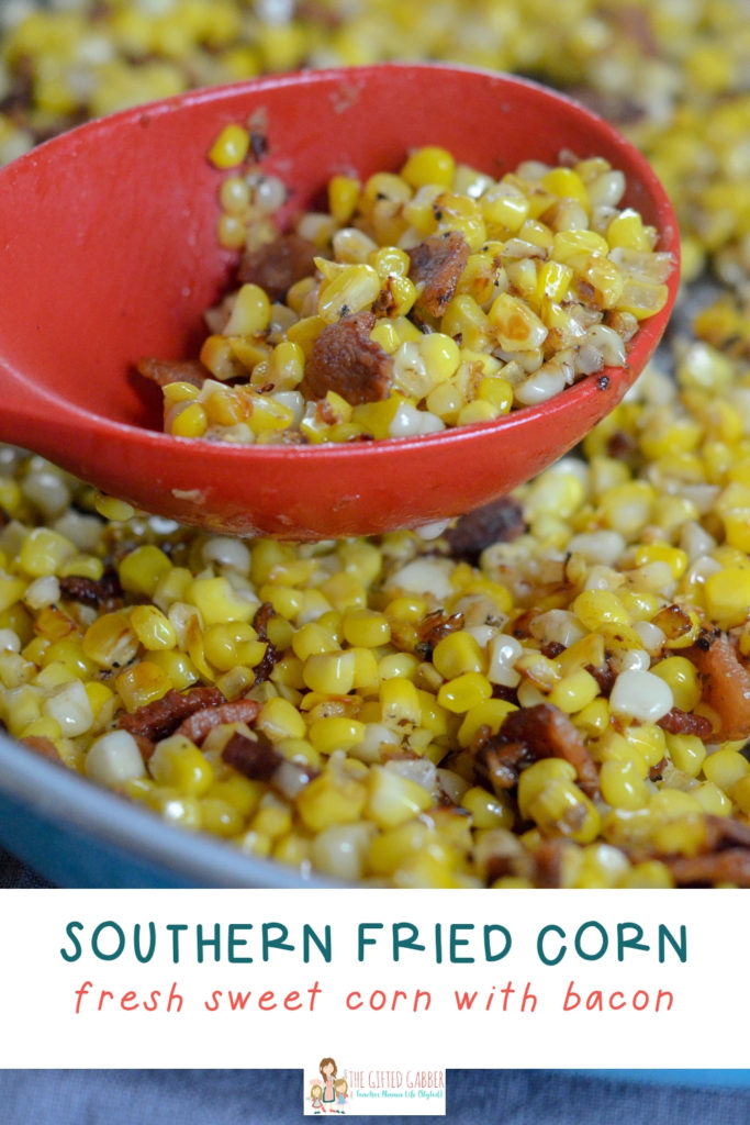 southern fried corn with bacon in a blue skillet with a red spoon 