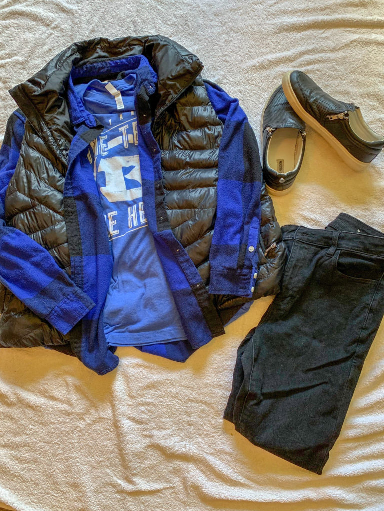 blue shirt with plaid shirt and black vest, black jeans, and sneakers flat lay