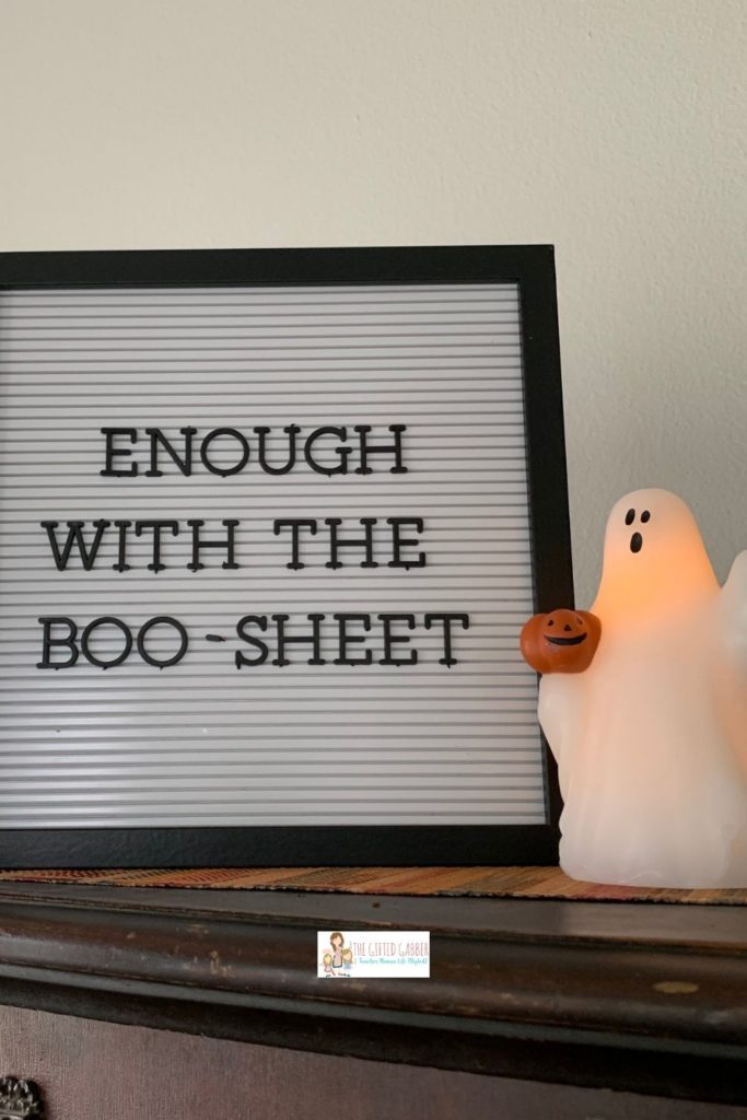 a boo-sheet quote on white letter board beside LED ghost candle
