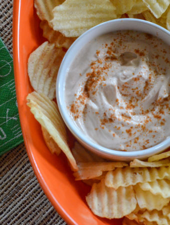 bbq sour cream dip in white bowl with potato chips in orange platter