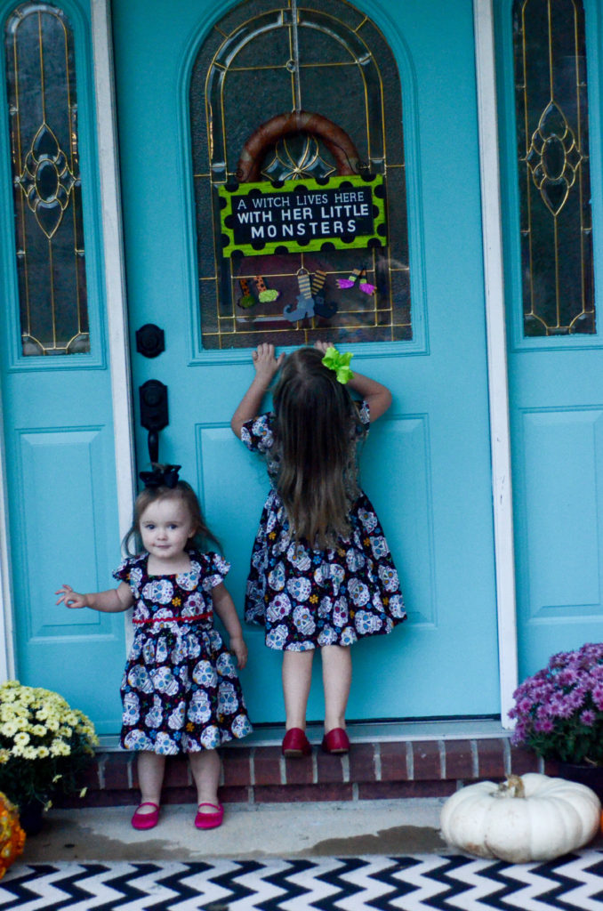 little girls go in turquoise door with Halloween witch quote on door 