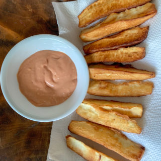 yuca fries with spicy dip in a deep white bowl