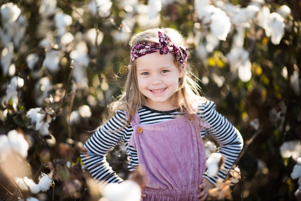 little girl in dusty muave romper in cotton field pictures