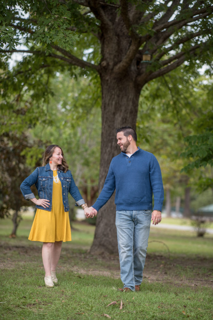 husband and wife in park wearing navy blue and mustard yellow outfits during a fall family photoshoot