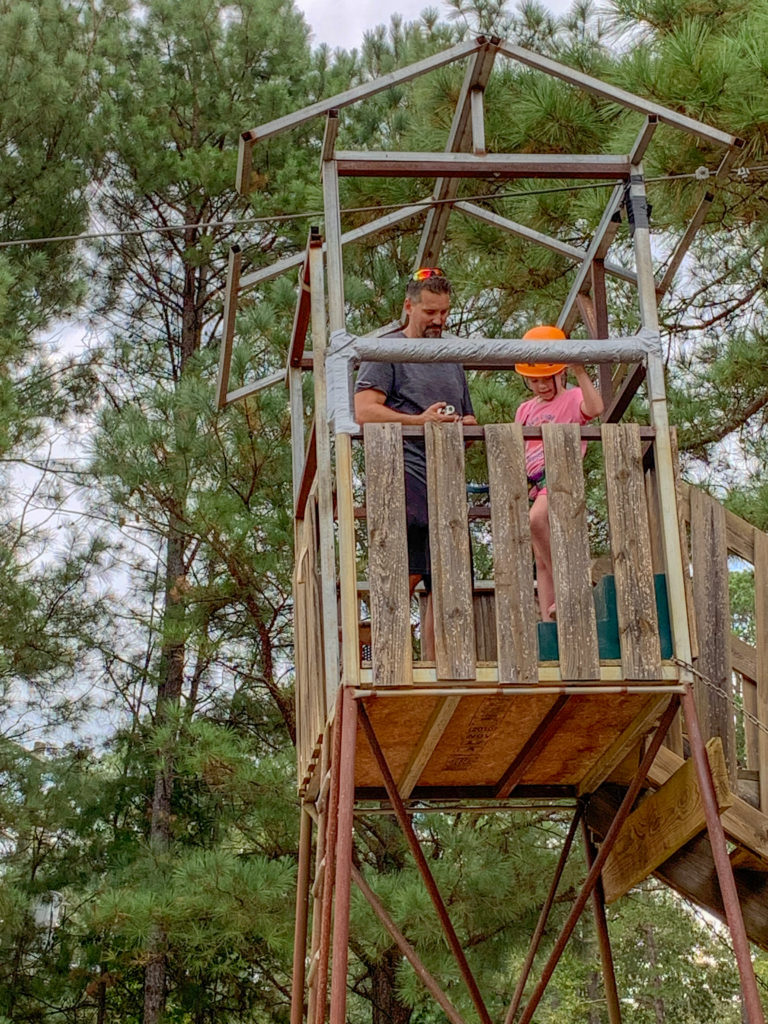man helps little girl get ready for zip line at Family Farm in Arkansas