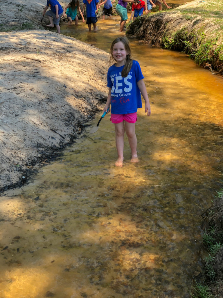 little girl walks in creek on field trip to Family Farm in Malvern, AR
