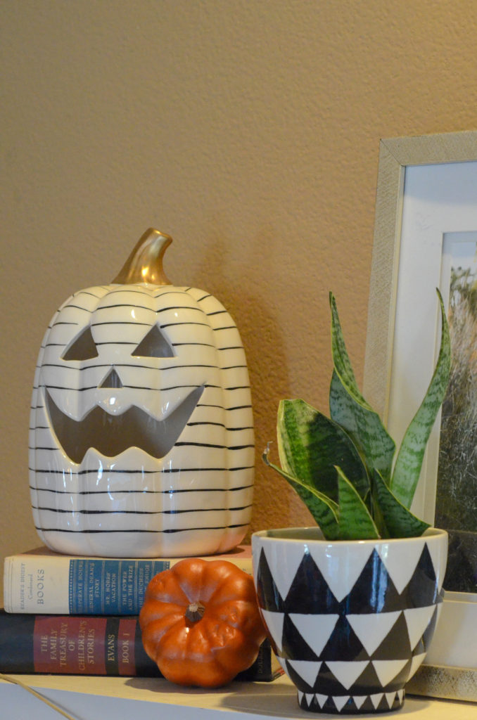 striped halloween jack o lantern with halloween plants as halloween plant decorations on mantle 
