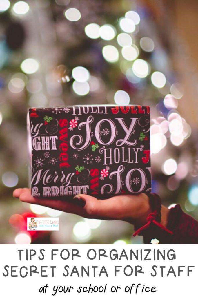 woman holds a wrapped Secret Santa gift in front of bright Christmas tree