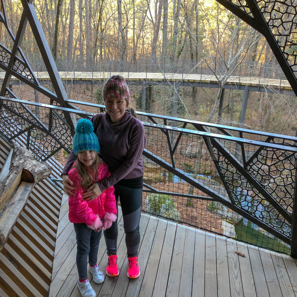 a mom and daughter smile while standing in a tree house in Arkansas 