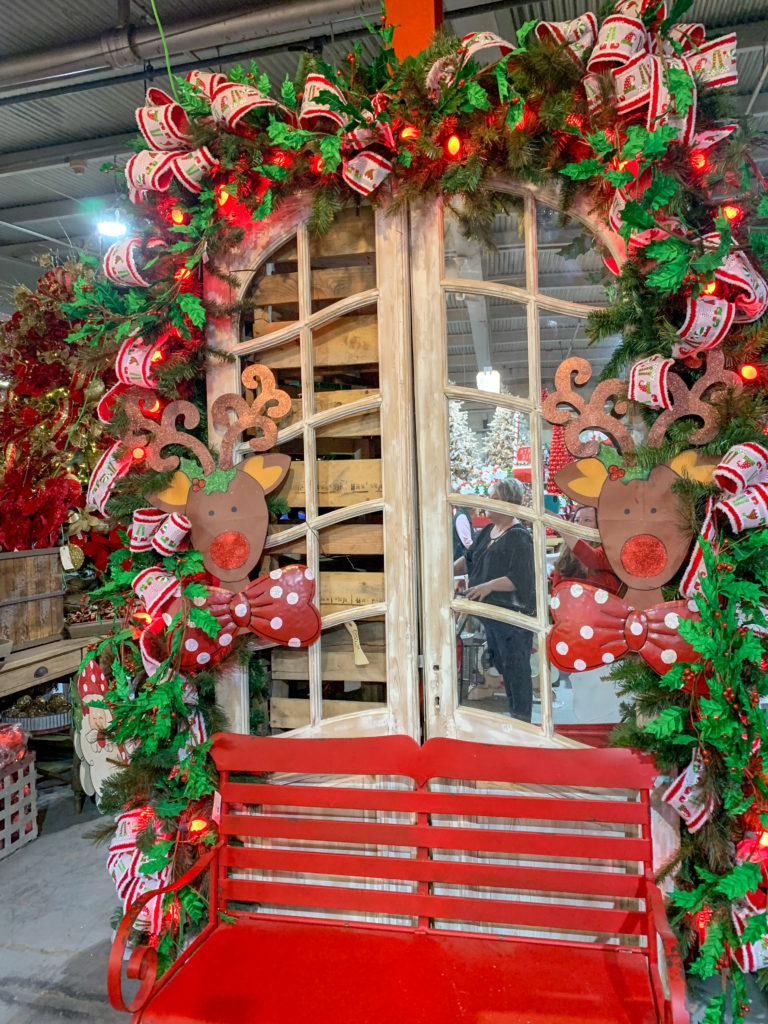 reindeer decorations on festive garland with white mirrored shutters and red bench and Guess and Company Christmas Warehouse 
