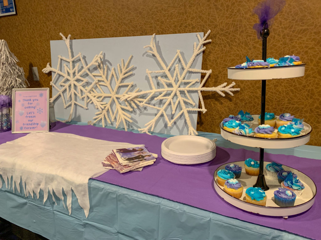 Frozen party table at movie theater birthday party with snowflake party decorations