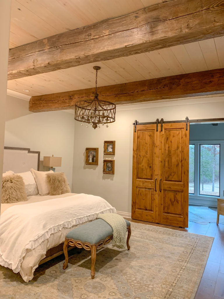 modern farmhouse bedroom with wood beam ceiling and barn door