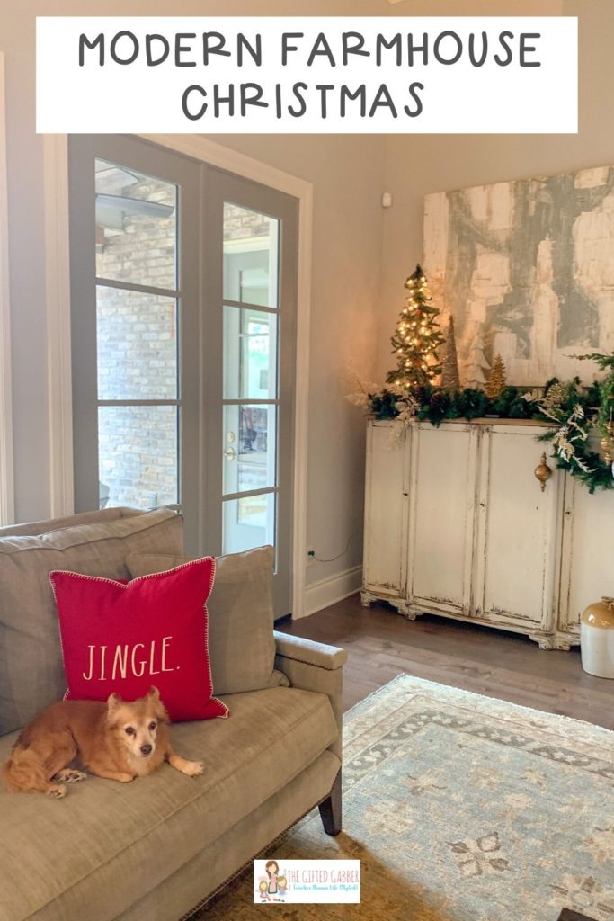 dog lounges on couch in modern farmhouse living room with Christmas decorations in background