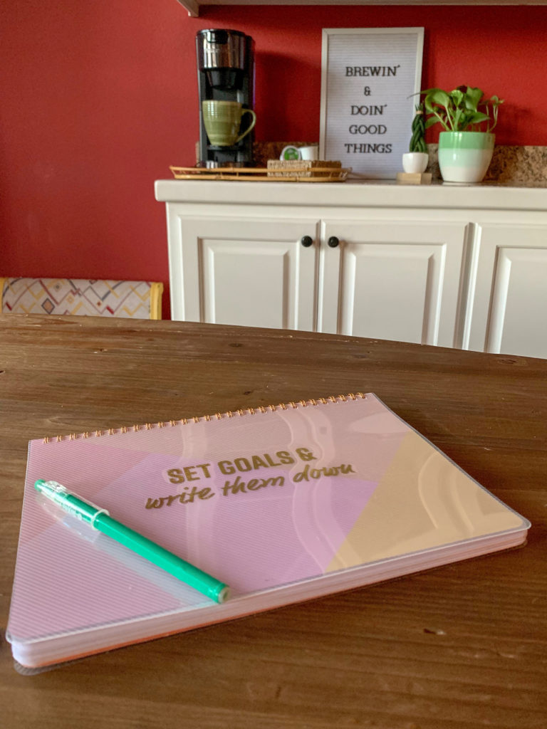 planner and pen on table with coffee pot in background 