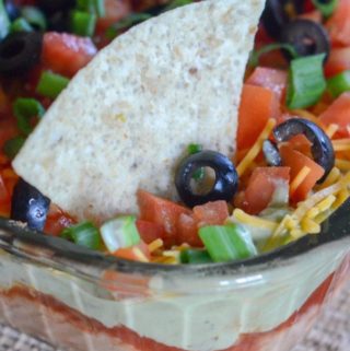 layered taco dip with chip in glass dish