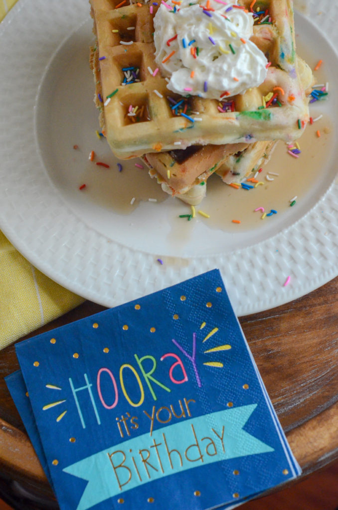 blue birthday napkin and stack of birthday cake waffles on white dish