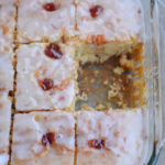 lemon strawberry poke cake in a glass cake pan with one slice missing