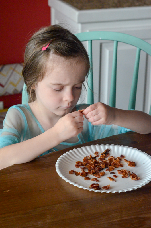 little girl breaks bacon into small pieces