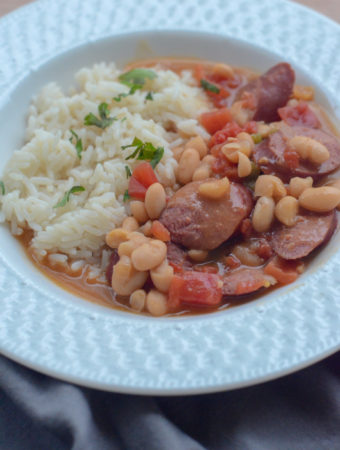 white beans and sausage soup with rice in white weaved dish