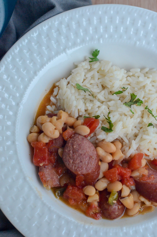 shallow white bowl with white white beans and rice with sausage and tomatoes