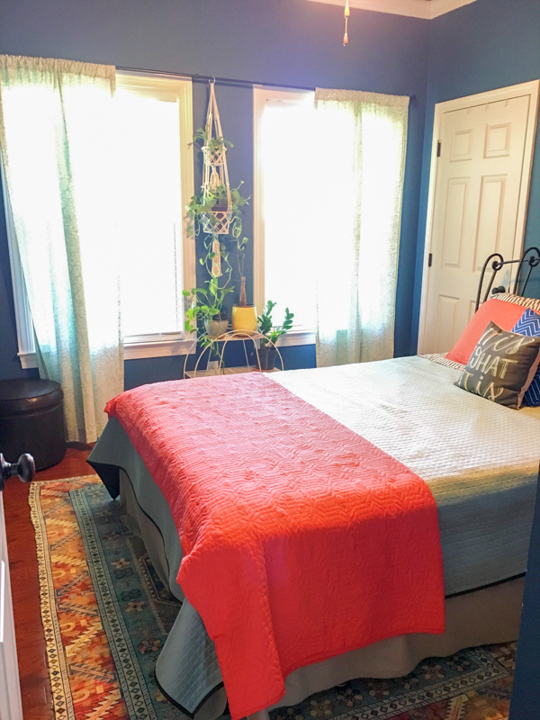 navy blue guest room with orange quilt on bed