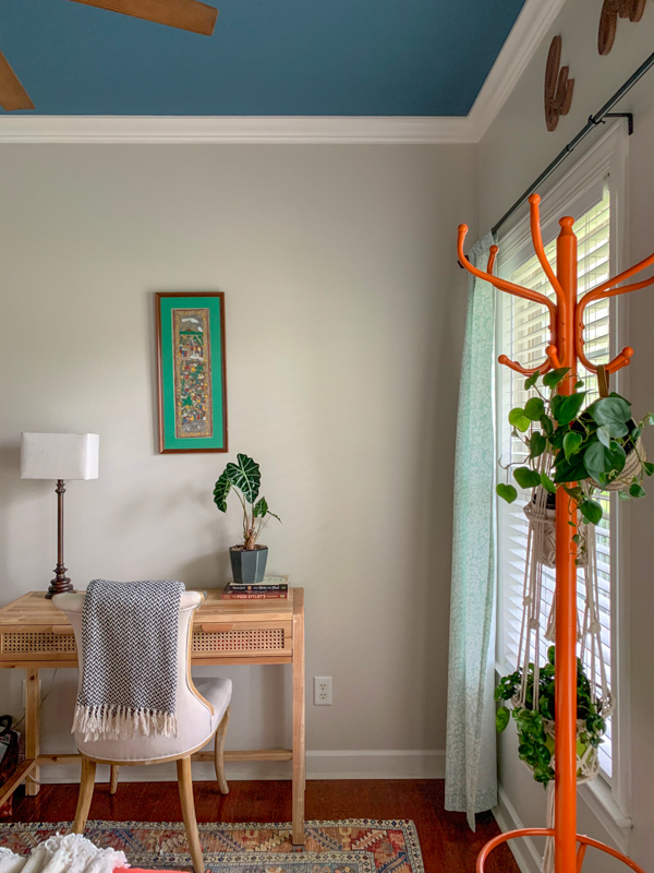 chair and table in home office guest room with orange coat tree as plant stand