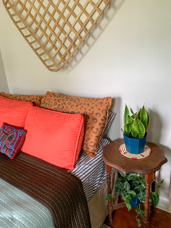 a Panamananian mola pillow on a bed with orange pillows in an office guest room combo
