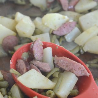 smoked sausage potato green beans sheet pan meal on black plate with sheet pan in back